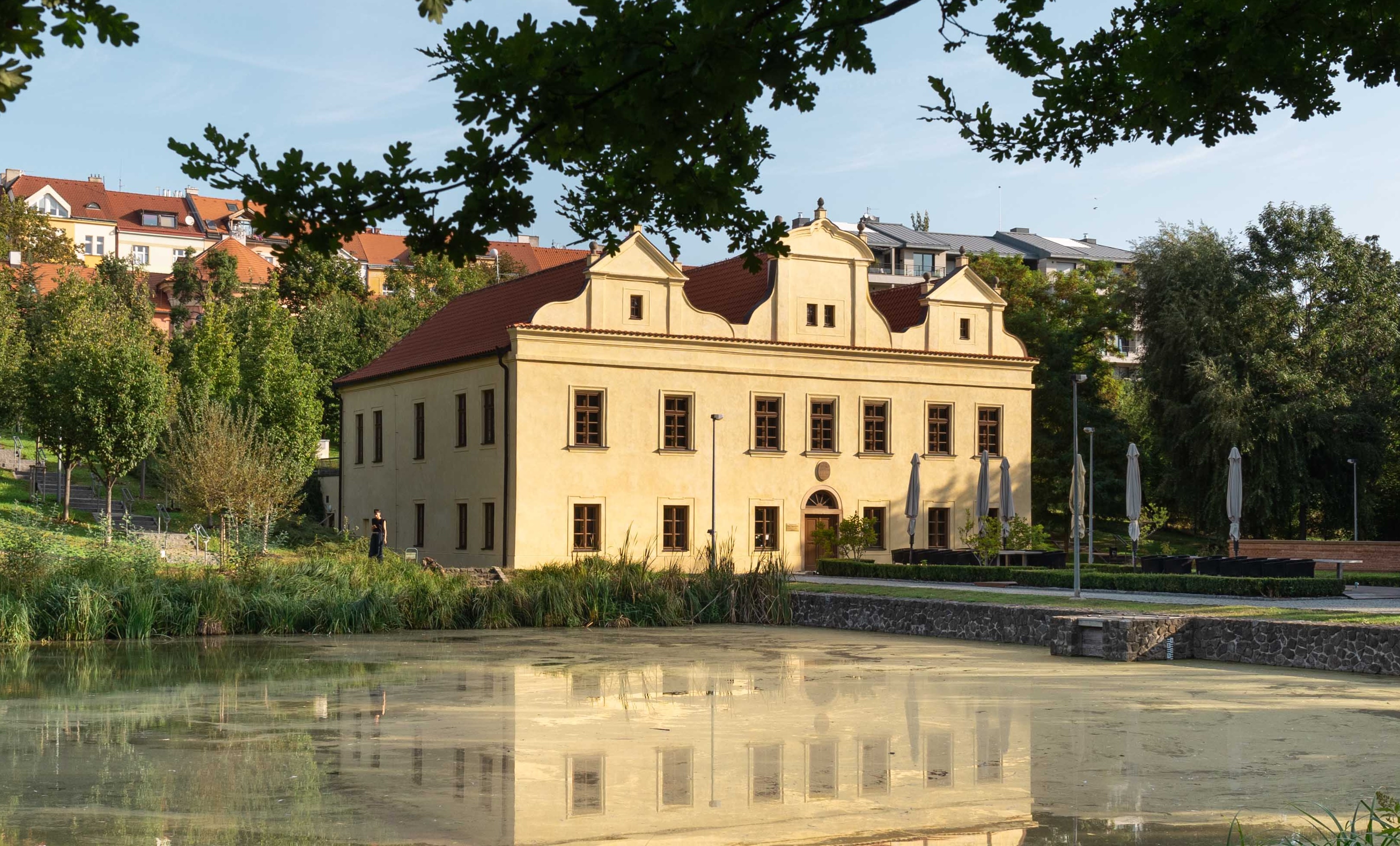 A private villa in Prague, reflected in the pond beside it and framed by trees
